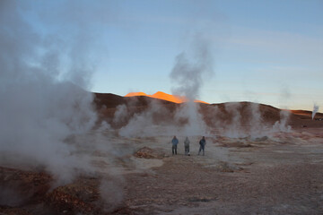 Silhuetas de três homens observando o geyser do Sol de la Mañana, na Bolivia