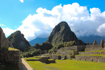 Monte Huayna Picchu, e em primeiro plano gramado e vista parcial das ruinas incas de Machu Picchu - obrazy, fototapety, plakaty