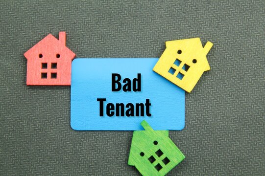 Colored Wooden Houses And Blue Paper With The Word Bad Tenant