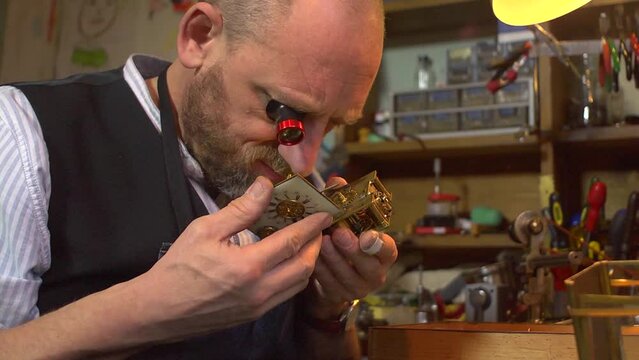 Clockmaker working on a carriage clock - inspection of movement and face