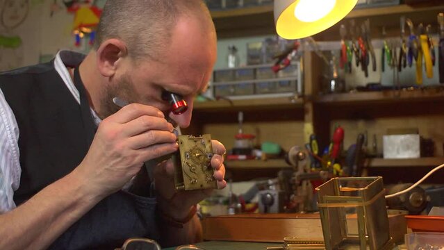 Clockmaker working on a carriage clock - inspection of works