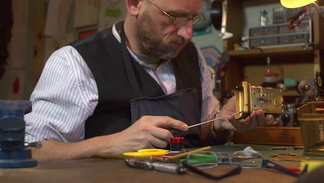 Clockmaker working on a carriage clock - closing the case with screwdriver
