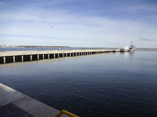 Obraz premium Seascape in early morning to stone pier with old boats moored. Ripple on navy water and blue sky. Noblessner, Tallinn, Estonia, Europe. April 2022
