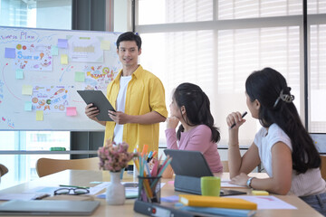 Asian male business team leader giving presentation start up business strategy for diverse employees in meeting.