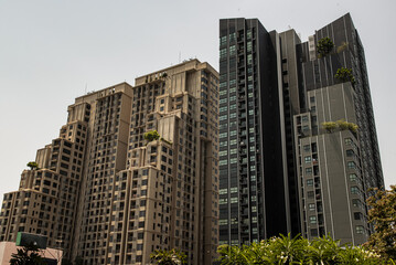 Obraz premium Bangkok,Thai-Apr 14,2022 : Architectural view of Overlapping city skyscrapers. Modern high-rise buildings with repeating structure glass. Angular geometric of building design, Selective focus.