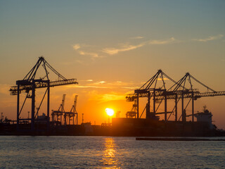 Fototapeta na wymiar Beautiful sunset above port on sunset time with silhouettes of cargo cranes. Industrial black sea port Odesa, Ukraine with a lot of cranes, cabins, boxes and tanks by the water on colorful sunset