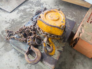 orange hook with sling belt and chain block or chain hoist which is placed on a cement floor,...