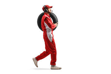 Full length profile shot of a race team member carrying a car tire