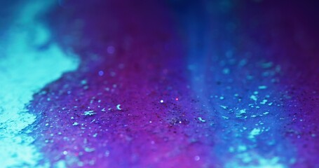 Fototapeta premium Glitter ink flow. Color fluid texture. Bokeh light. Defocused fluorescent purple pink blue shimmering particles paint abstract art background.