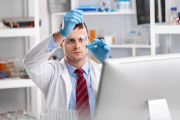 Viorolog researcher examining a sample from test tube working in a modern equipped laboratory.