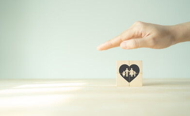 Family protection, care and health care concept. Homeless charity support, family mental health, international day of families.  Showing hand to protect the family on wooden cubes. Warm background.
