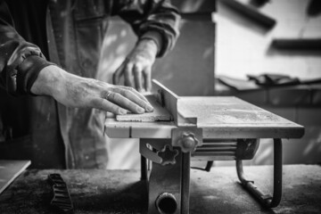 Unrecognizable Man working And Cutting The Wood On A Machine Tool Called A Table Saw In A Carpentry Workshop. Person Doing DIY In The Garden Of His House. DIY And Craft Concept. Detail