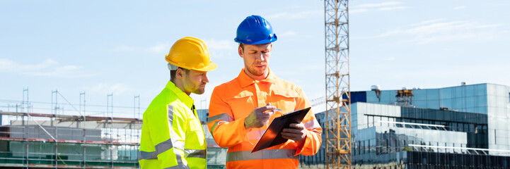 Two Male Engineers With Clipboard Working At Construction Site