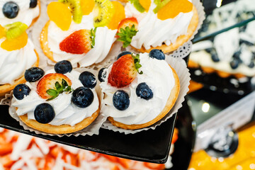 Cakes with cream and berries. Trade in sweets in a confectionery shop. Close-up