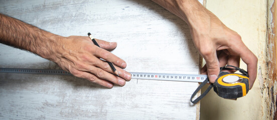 Carpenter marking laminate with tape measure and pencil.