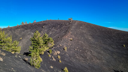 Man hiking around crater of Sartorio on volcanic landscape of volcano mount Etna, in Sicily, Italy,...