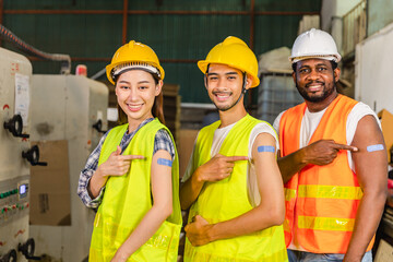 Asian young workers and African man pointing at his arm with a bandage after receiving the covid-19 vaccine.Vaccination for Essential Workers in healthcare at industrial factory.