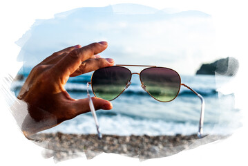 Hand holding stylish round sunglasses with brown lenses at sunset. Putting on sunglasses at sunny...