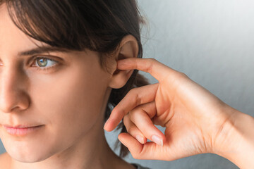 Woman putting a finger into her ear. Itchy ear isolated with copy space. otitis media