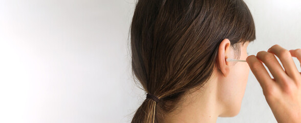 Naklejka premium Woman is cleaning ear with a cotton swab.