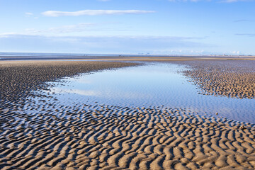 Low tide calm conditions and a sunny April morning at Dymchurch beach on the coast of Kent south...