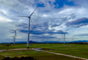 Wind farm or wind park, with high wind turbines in the setting sun for generation electricity with copy space. Green energy concept to reduce climate change and global warming