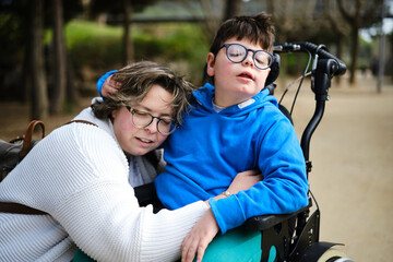 Mother hugging her disabled son in a wheelchair while enjoying the day outdoors together.