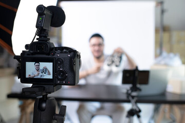 Young attractive Asian man blogger or vlogger looking at camera reviewing product. Modern...