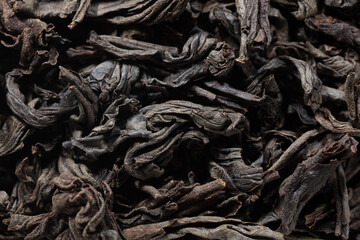 Dried black tea leaves as background.