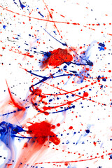 Drops of red and blue paint on a white background.