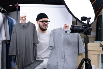Young attractive Asian man blogger or vlogger looking at camera reviewing product. Modern...