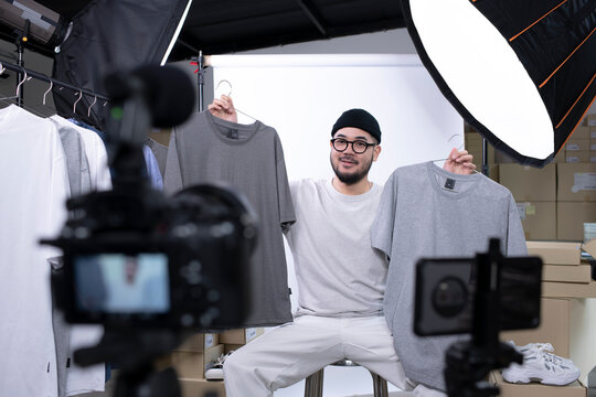 Young attractive Asian man blogger or vlogger looking at camera reviewing product. Modern businessman using social media for marketing. Business online influencer on social media concept.