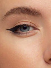 Glamour close-up portrait of beautiful woman model face with winged black eyeliner make-up, clean skin on white background. Long eyelashes and thick eyebrows.