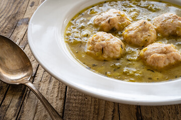 Boiled pork meatballs in onion soup on wooden table
