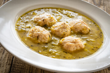 Boiled pork meatballs in onion soup on wooden table
