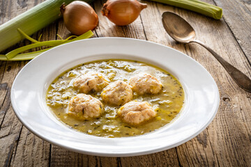 Boiled pork meatballs in onion soup on wooden table
