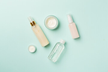 Different cosmetic bottles on color background, top view