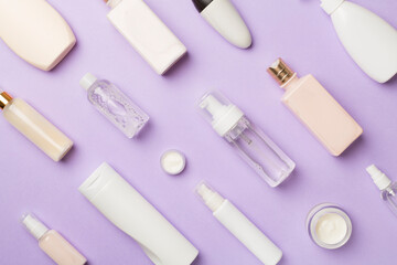 Different cosmetic bottles on color background, top view