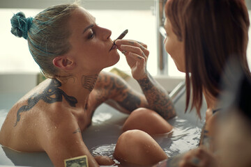 Hot lesbian couple having fun in bath tub; Hedonistic lifestyle