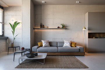 Living room in loft style, apartment with open plan loft style, gray sofa in the loft interior