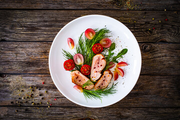 Roasted pork loin slices with dill and cherry tomatoes on wooden table