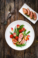 Roasted pork loin slices with dill and cherry tomatoes on wooden table