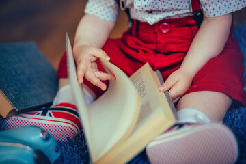 child holding a book in his hands sitting on the floor