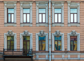 Fototapeta na wymiar Balcony and many windows in a row on the facade of the urban historic apartment building front view, Saint Petersburg, Russia 