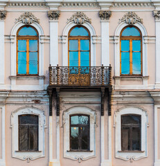 Fototapeta premium Balcony and several windows in a row on the facade of the urban historic apartment building front view, Saint Petersburg, Russia 