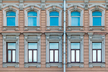 Fototapeta na wymiar Many windows in a row on the facade of the urban historic apartment building front view, Saint Petersburg, Russia 