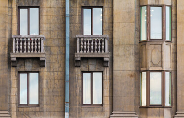 Two balconies and several windows in a row on the facade of the urban historic apartment building front view, Saint Petersburg, Russia
