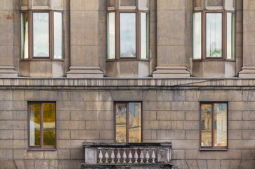 Balcony and several windows in a row on the facade of the urban historic apartment building front...