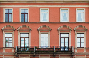 Obraz premium Balcony and many windows in a row on the facade of the urban historic apartment building front view, Saint Petersburg, Russia 
