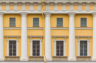Fototapeta na wymiar Columns and several windows in a row on the facade of the urban historic apartment building front view, Saint Petersburg, Russia 